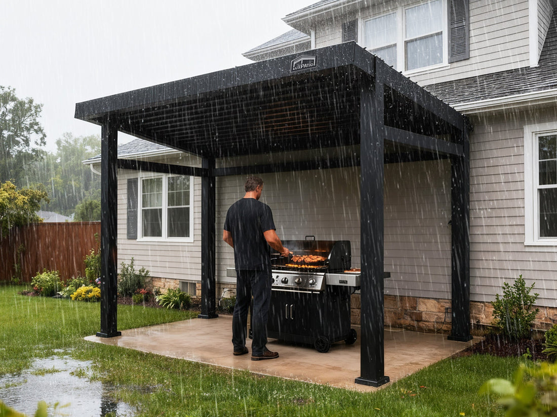 A man grilling outdoors under a sturdy, modern black pergola attached to a suburban house while heavy rain is falling, demonstrating the structure's weather protection.