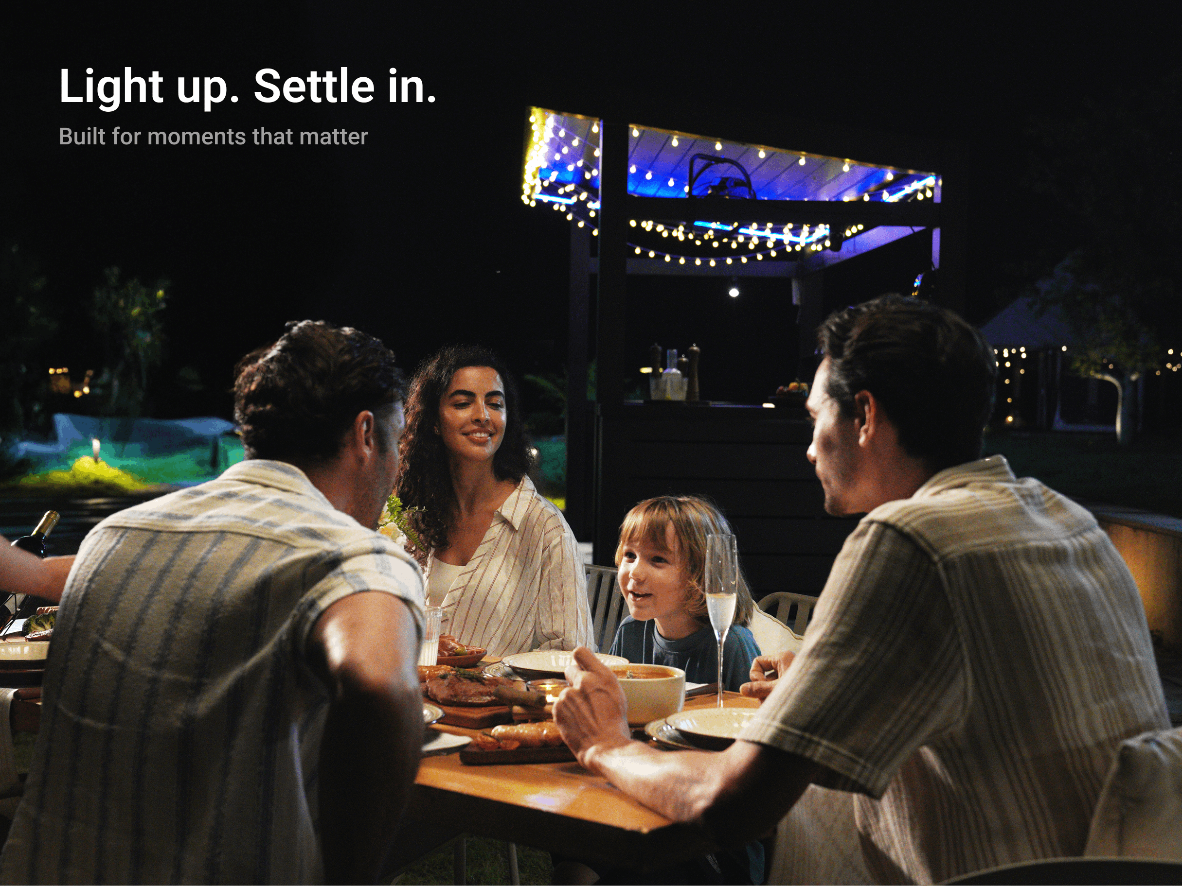 Family dining under LuxPatio louvered pergola with evening string lights and adjustable weather protection.