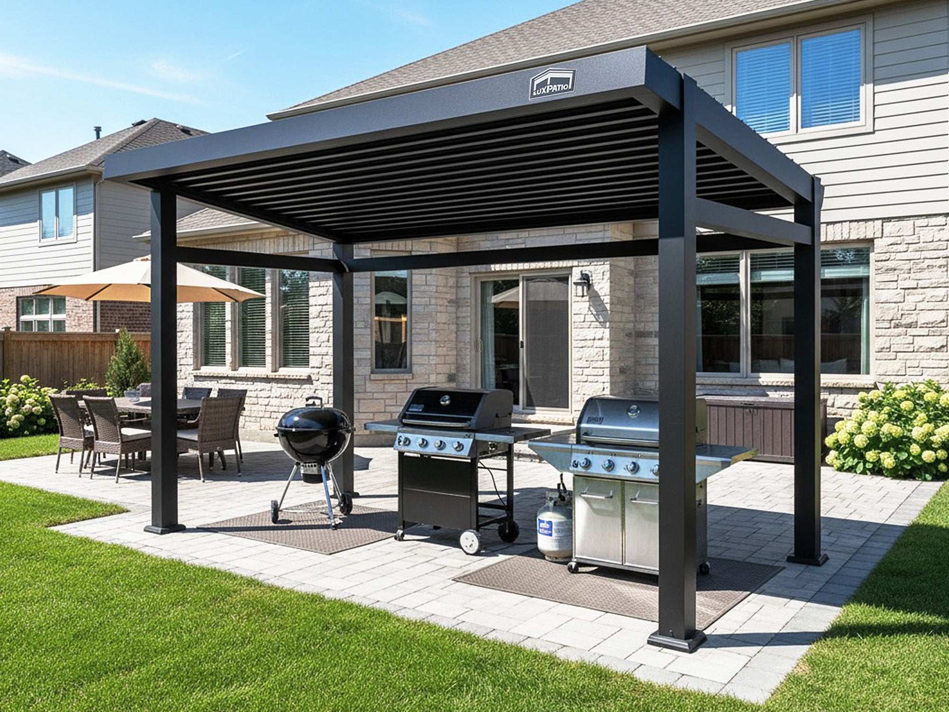 A large black pergola with a louvered roof covering two grills on a paver patio in a suburban backyard.